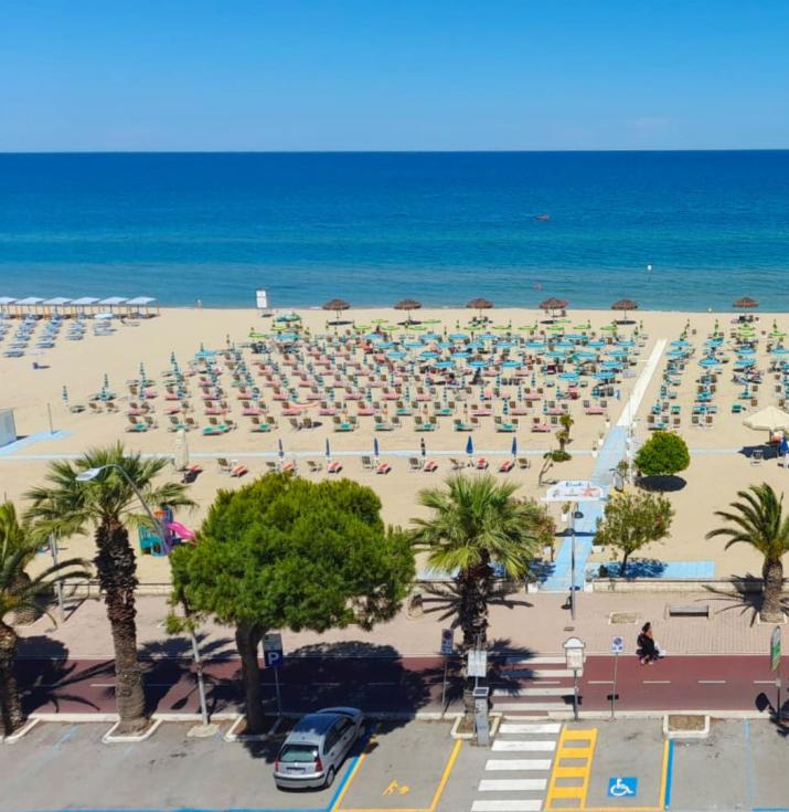 Spiaggia sabbiosa con ombrelloni e mare blu, vista panoramica.